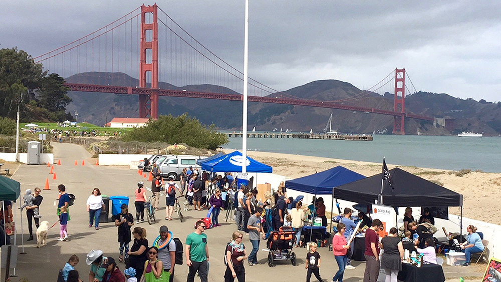 people approaching informational tents in front of the golden gate bridge