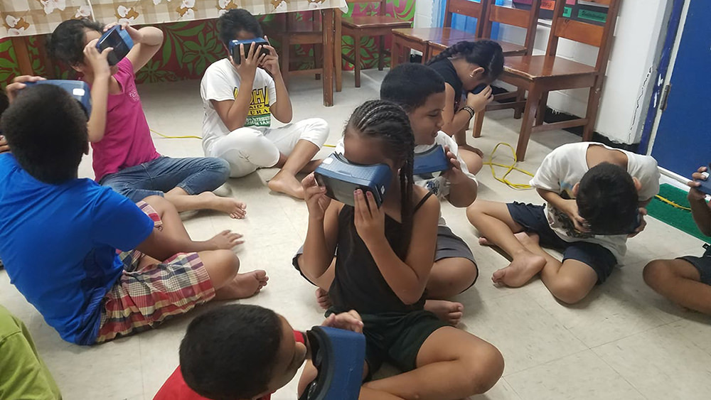 students sitting on the floor looking at virtual reality viewers