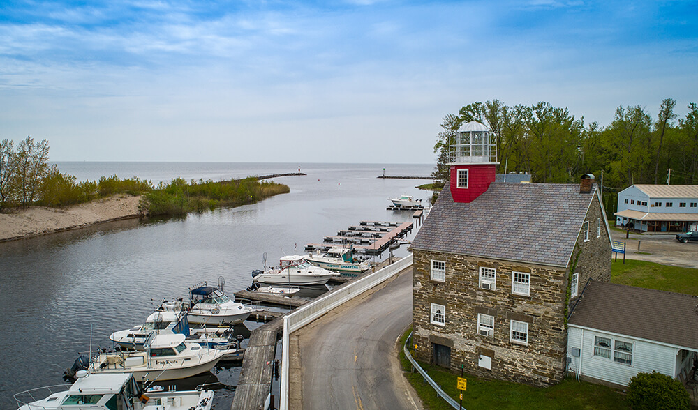 An arial view of a small light house and docked boats