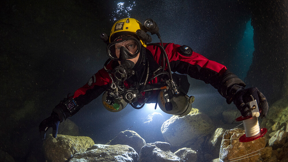 a diver swims through an underwater cave