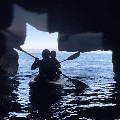 Two kayakers entering a cave