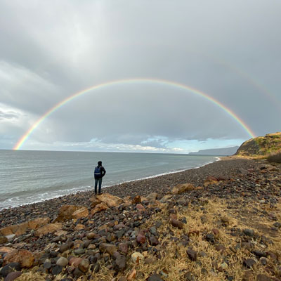Rainbow over beach with person looking out