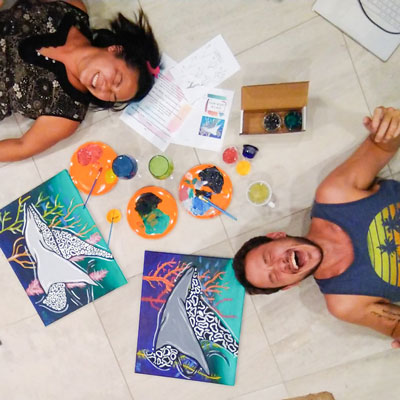 two people laying down with ray paintings laughing