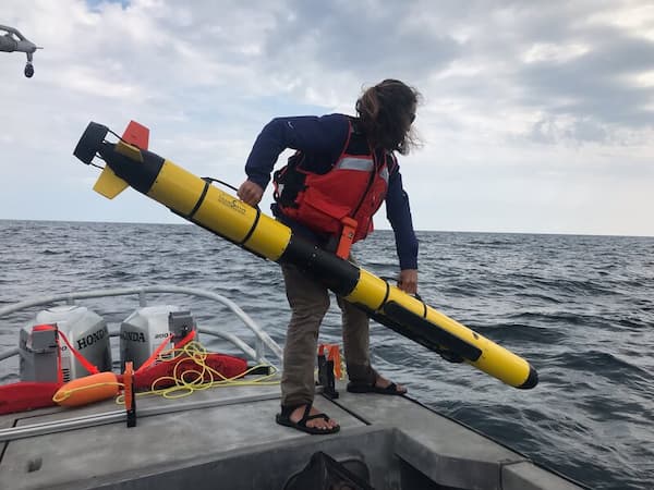 a person deploying a auv over the side of a ship