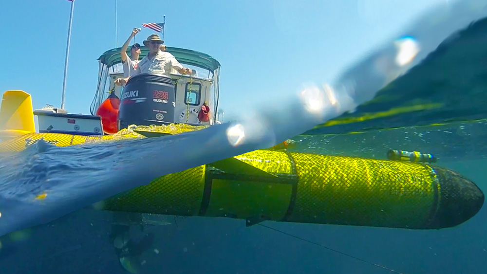 glider below the water as researchers look on from a boat