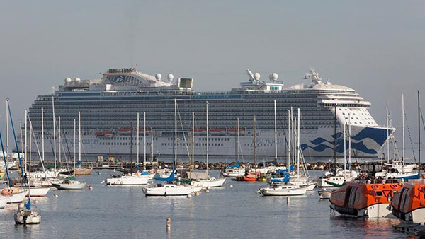 many small boats with a large cruise ship in the background