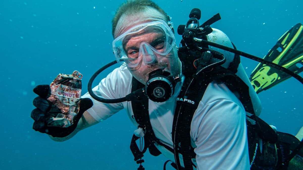 A scuba diver holding a can under water