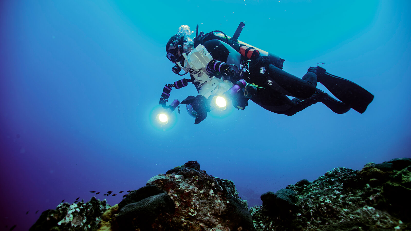 a scuba diver holds a camera with bright video lights