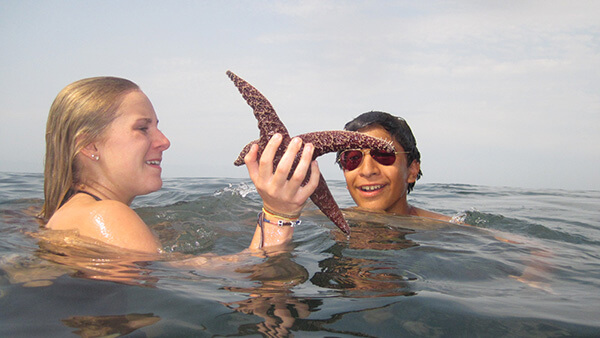 Hannah MacDonald in the water holding a sea star