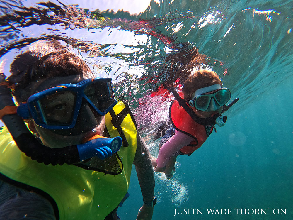 selfie of photographer and their daughter, both in snorkeling masks underwater