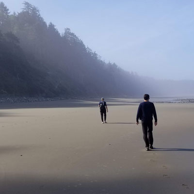 two people walk along the foggy beach