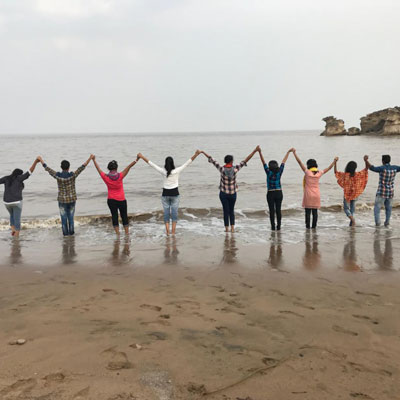 group of people holding hands, arms raised up, posed in front of the ocean