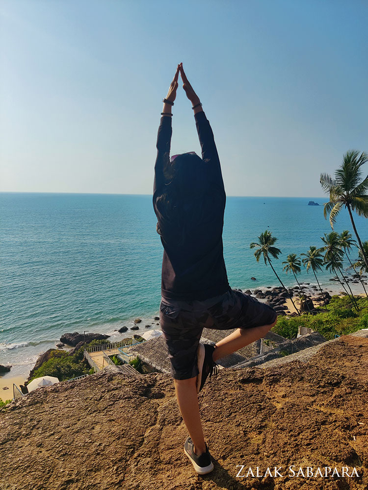 person in a standing yoga pose, in front of the beach
