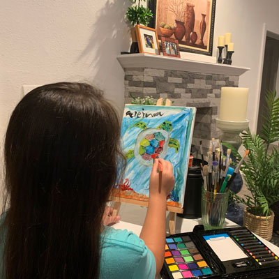 Young person painting a picture of a turtle in their home.