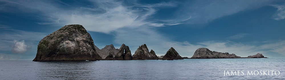 panoramic of rocky cliffs rising from the ocean. 