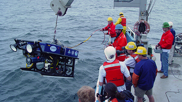 a remotely operated vehicle being lowered into the water from a vessel