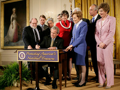 President George W Bush signing a document at a podium