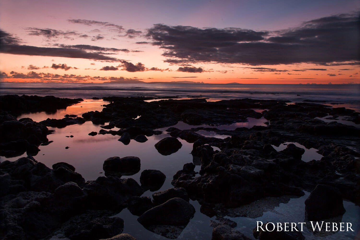 Warm sunrise over a tide pool with some clouds in the sky.