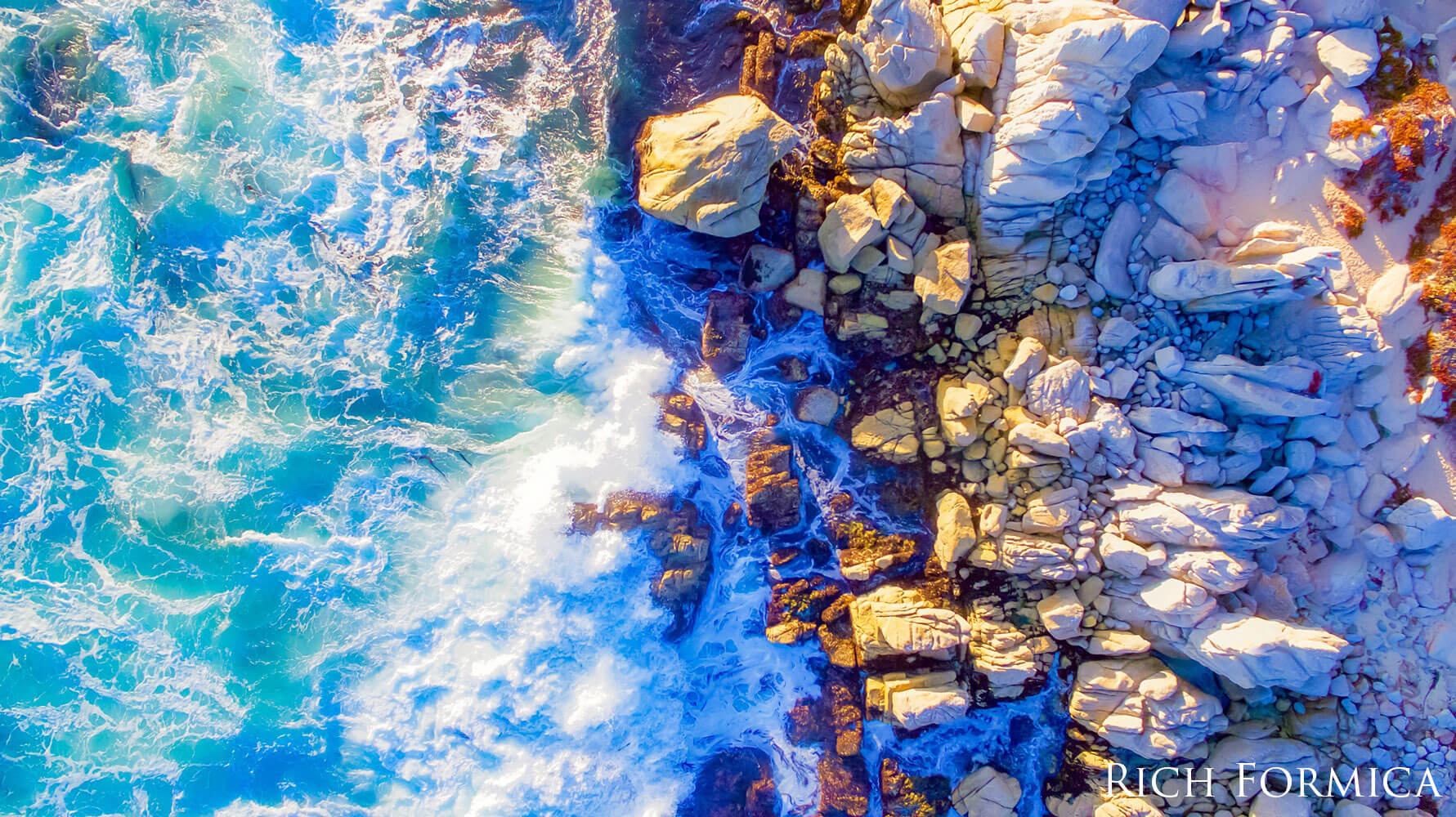 Aerial view of waves breaking on a rocky shoreline.