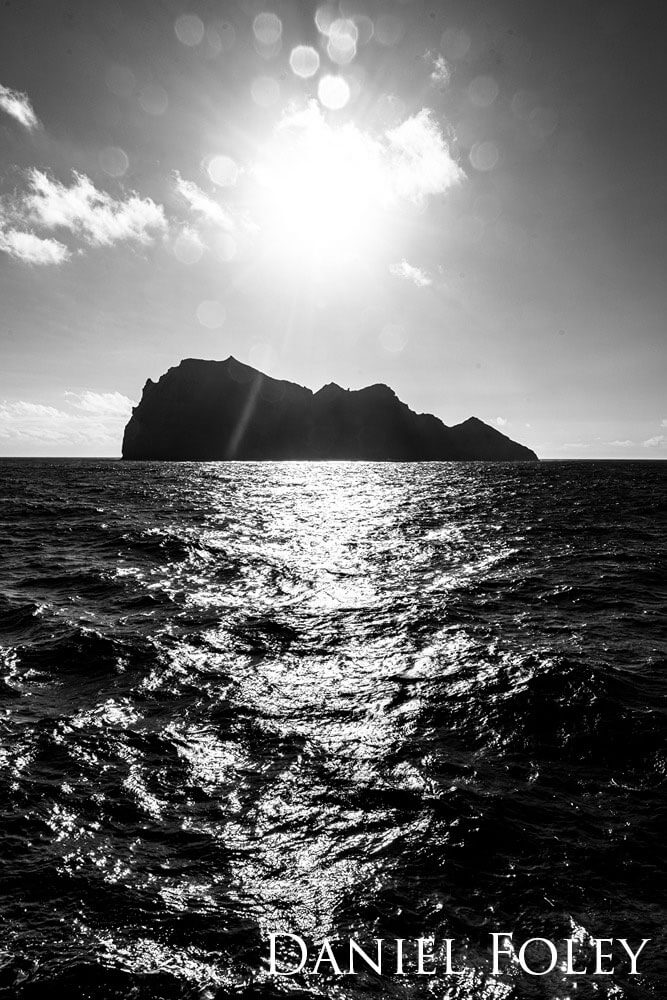Island with the sun shining overhead. Photo is taken in black and white.