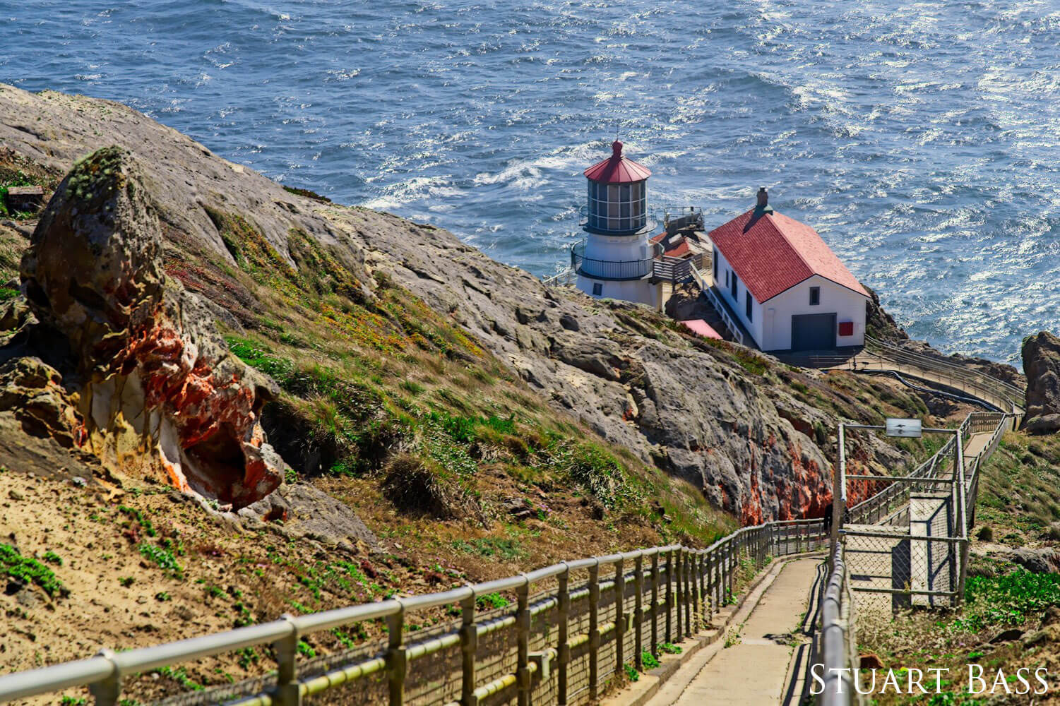 A path leading to a lighthouse overlooking the ocean.