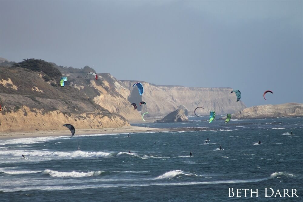 Group of kite surfers near the rocky terrain of Monterey Bay National Marine Sanctuary.