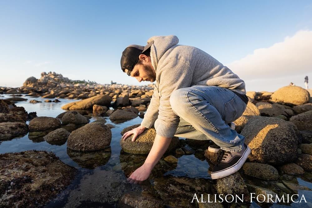 Man squatting near tide pool to get a closer look.