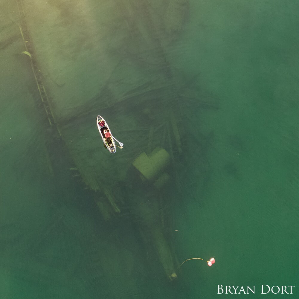 Aerial view of paddle boarder over a sunked ship.