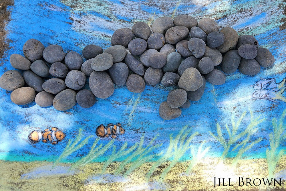 Manatee made out of rocks with chalk drawing surrounding it to symbolize Florida Keys National Marine Sanctuary.