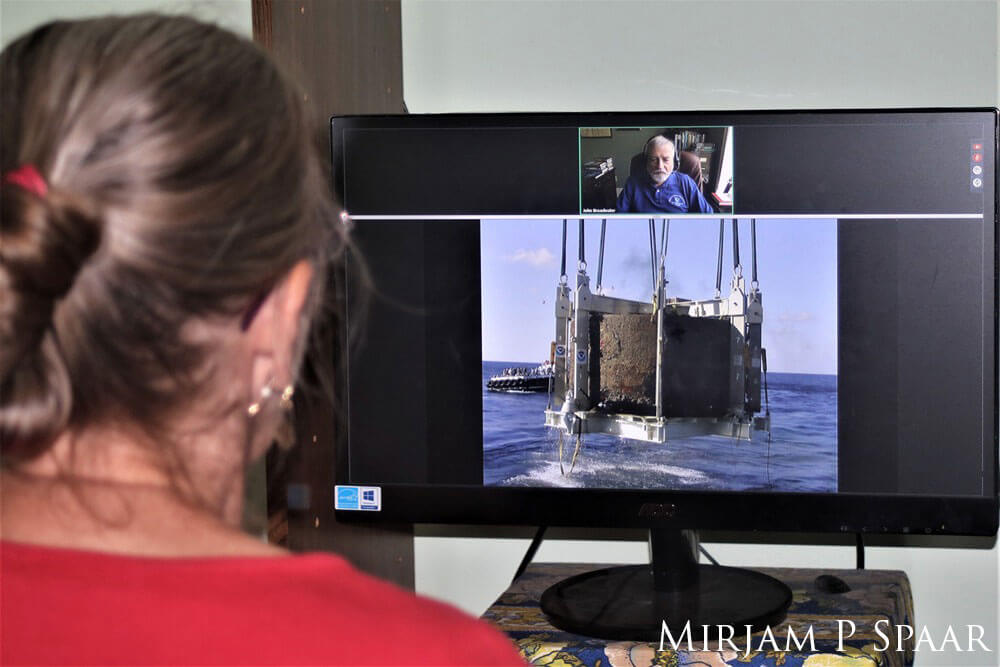 a person looking at a monitor, the monitor has a image of the uss monitor turrent being lifted out of the water