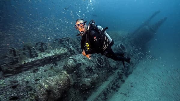 Diver looking at the camera while next to a shipwreck