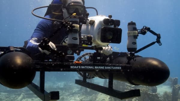 A diver holding a camera under water