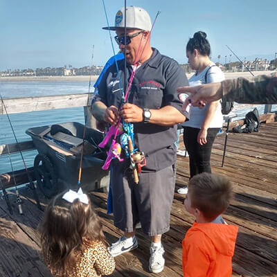 a man hands fishing rods to children