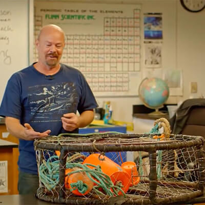 a person displays a fishing trap in a classroom