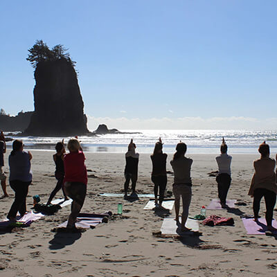 a group of people doing yoga on a beach