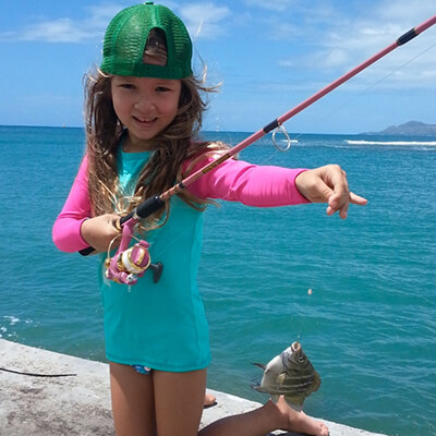 a girl shows off a small fish she caught