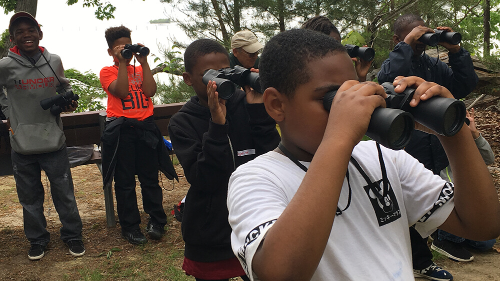 A group of kids look through binoculars
