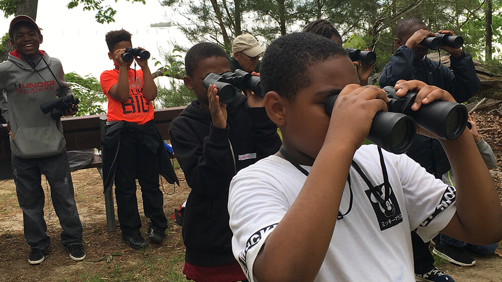 a group of kids look through binoculars