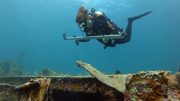 Diver uses tool to study a shipwreck