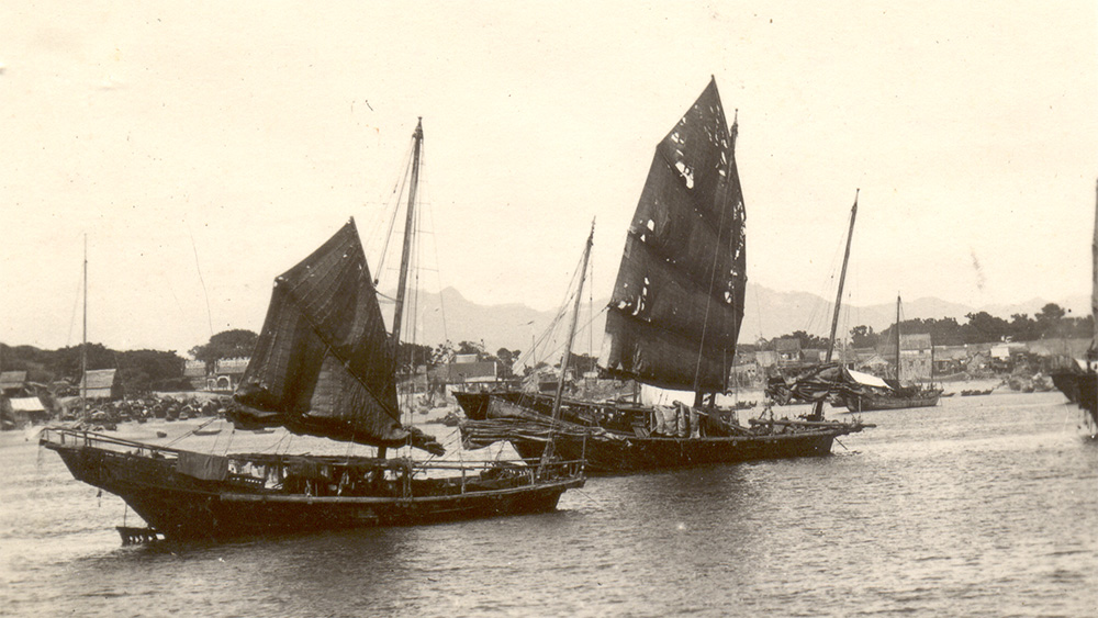a black and white photo of sailing vessels on the water