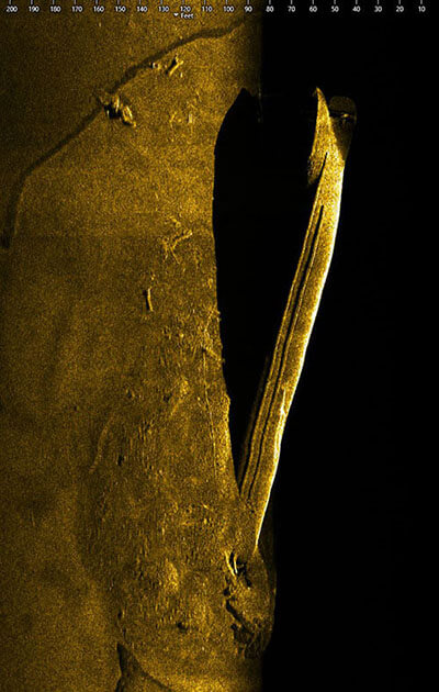sonar image of a shipwreck on the seafloor. The ship appears to be laying on its side.