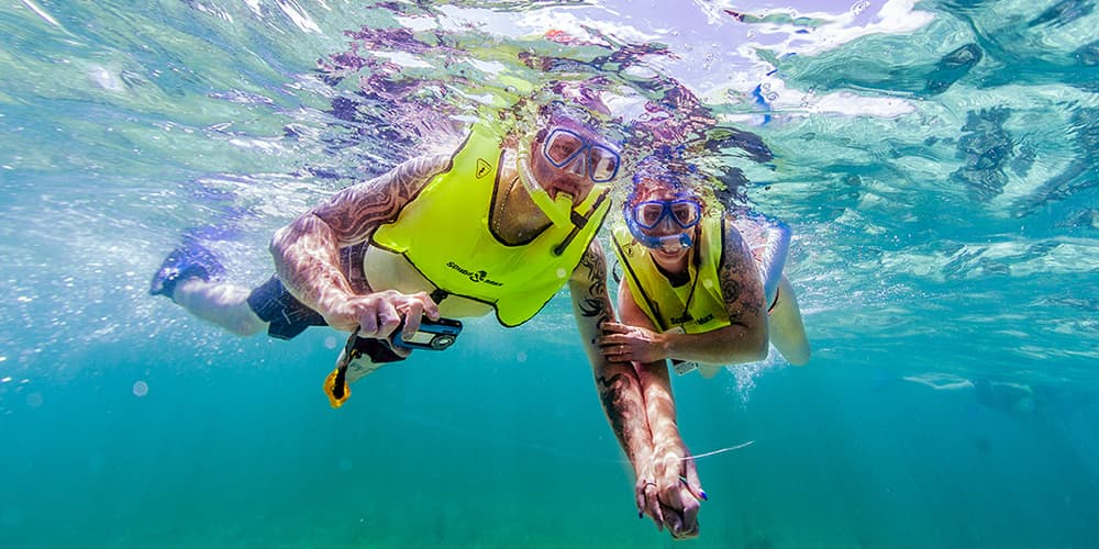 a man and woman holding hands while snorkeling