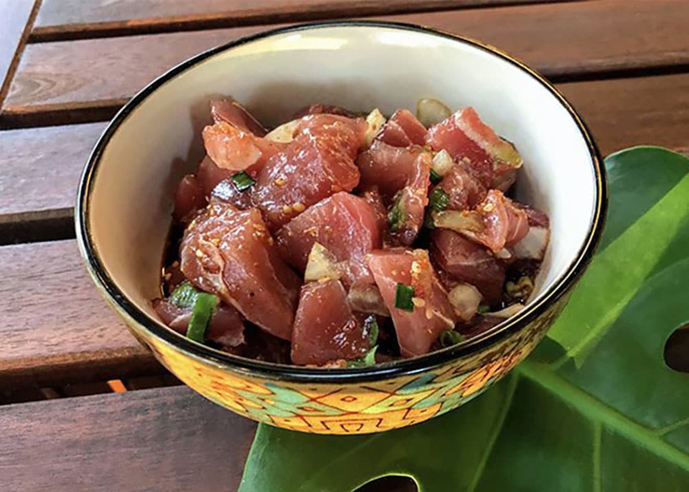 pieces of diced tuna in a bowl sprinked with sesame, green onion, and soy sauce