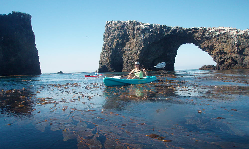 two kayakers paddle by Channel Islands arch rock