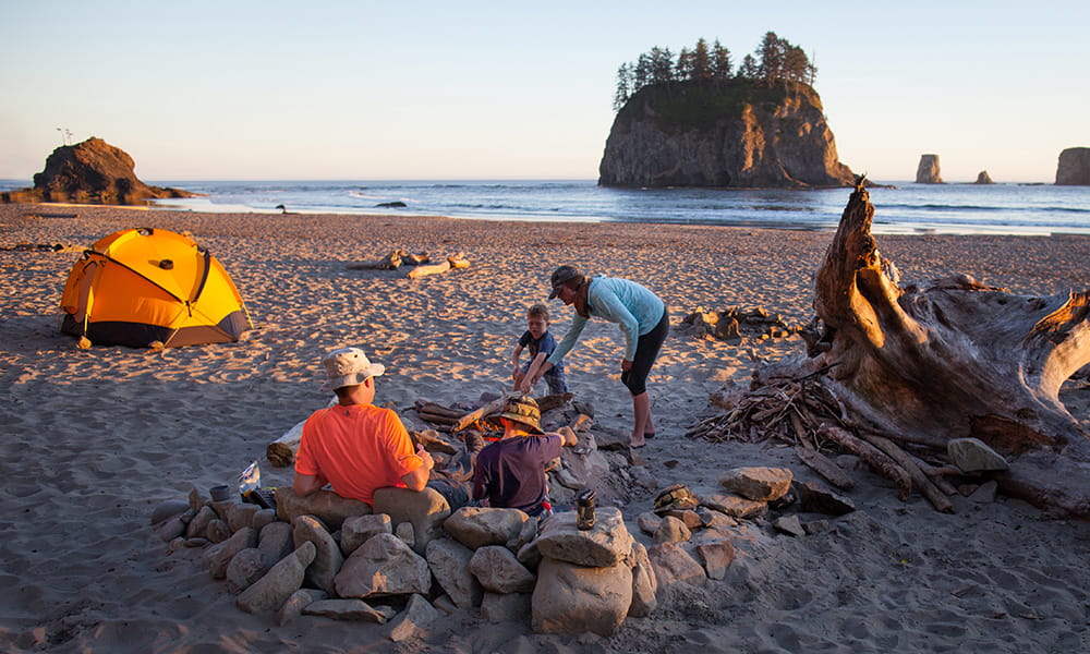 family preparing a camp fire on the beach