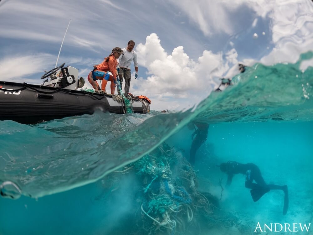 Marine Debris Technicians from PMDP Hawaii stand on a boat and remove a ghost net from the reef at Kamokuokamohoaliʻi, Papahānaumokuākea Marine National Monument.
