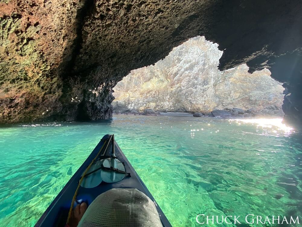 A kayak sits on clear water in a cave.