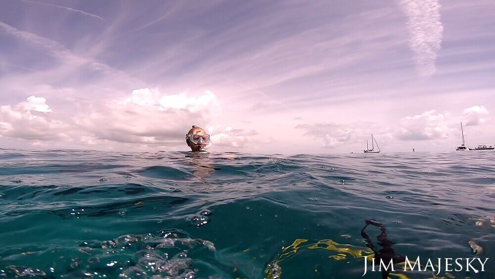A snorkeler wearing a mask breaks the surface of the water.