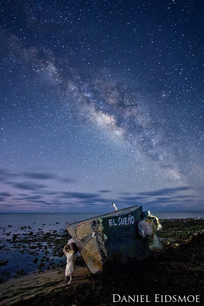 Migrant boat on shore with Milky Way in the sky.