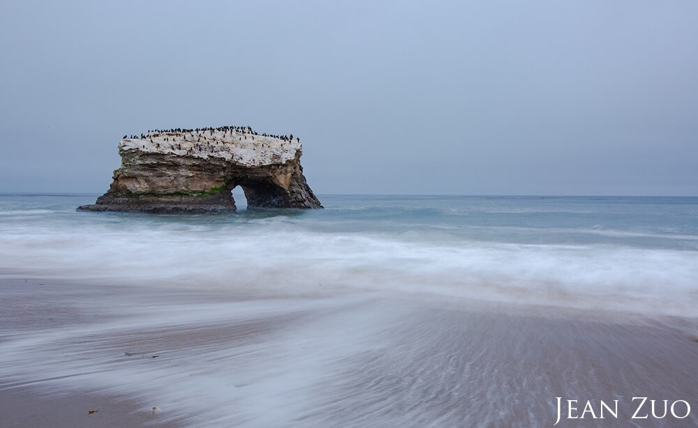 There was no sunset to capture in this overcast evening. A slow camera shutter makes the ocean water silky around the nature bridge.